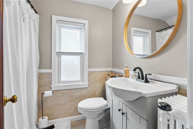 bathroom with vanity, toilet, and tile walls