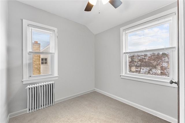 carpeted empty room with lofted ceiling, ceiling fan, radiator heating unit, and a wealth of natural light