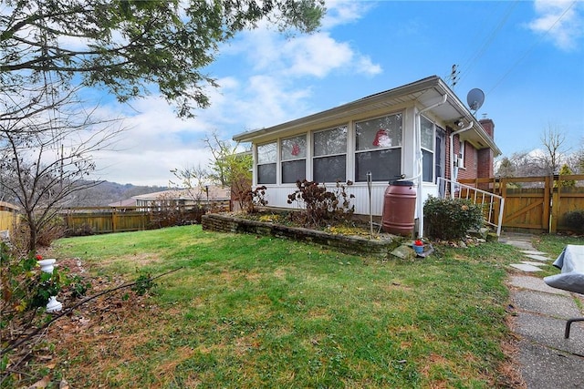 view of side of home with a lawn and a sunroom