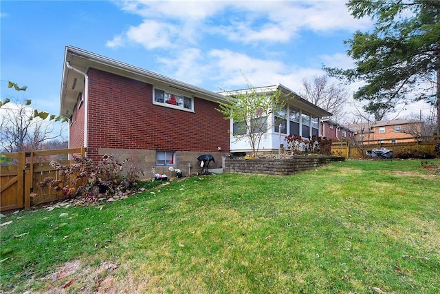 rear view of house with a yard and a sunroom