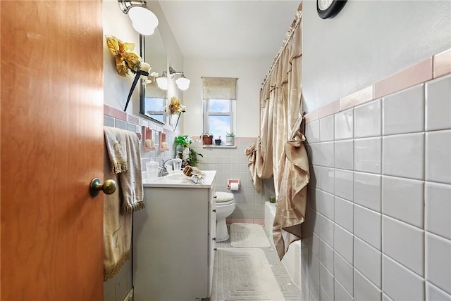 bathroom featuring vanity, toilet, and tile walls