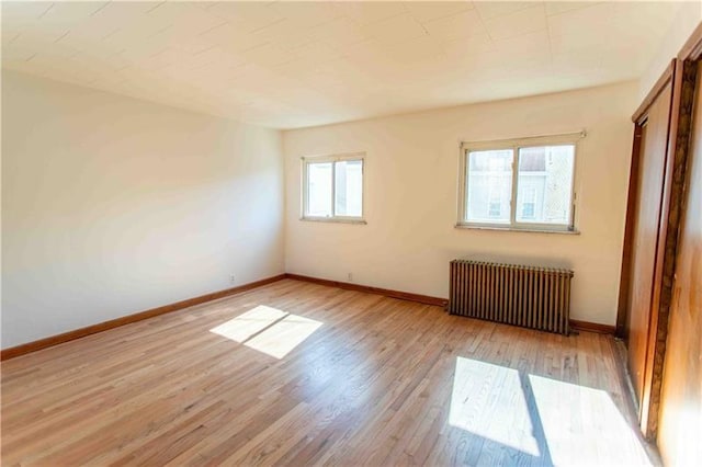 unfurnished room featuring light hardwood / wood-style flooring, plenty of natural light, and radiator