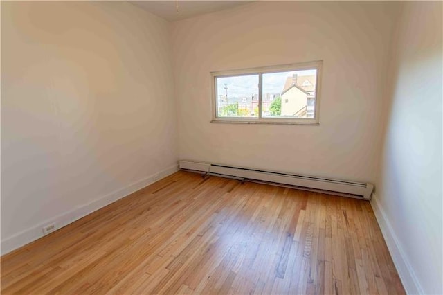 spare room with a baseboard radiator and light hardwood / wood-style floors