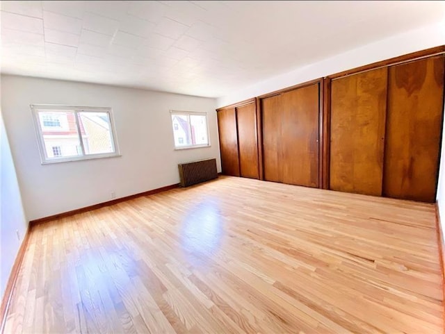 unfurnished bedroom featuring radiator heating unit and light hardwood / wood-style flooring