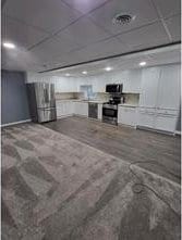 basement featuring stainless steel fridge and a paneled ceiling