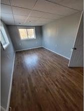 interior space featuring a drop ceiling and dark wood-type flooring