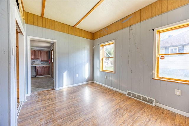 empty room with light wood-type flooring and wood walls