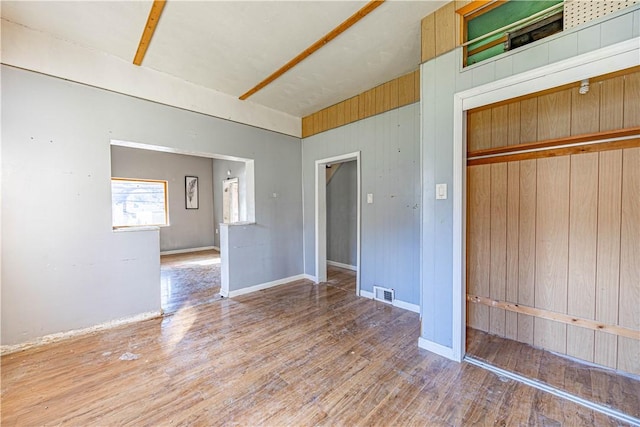 unfurnished room featuring hardwood / wood-style flooring and wooden walls