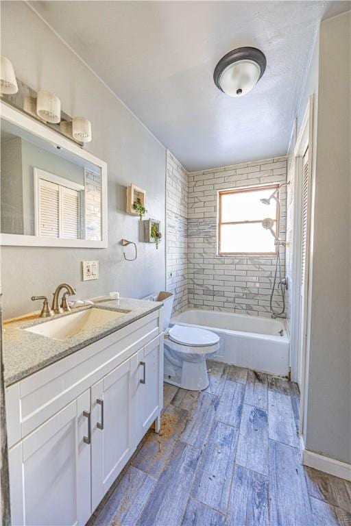 full bathroom with vanity, toilet, wood-type flooring, and tiled shower / bath