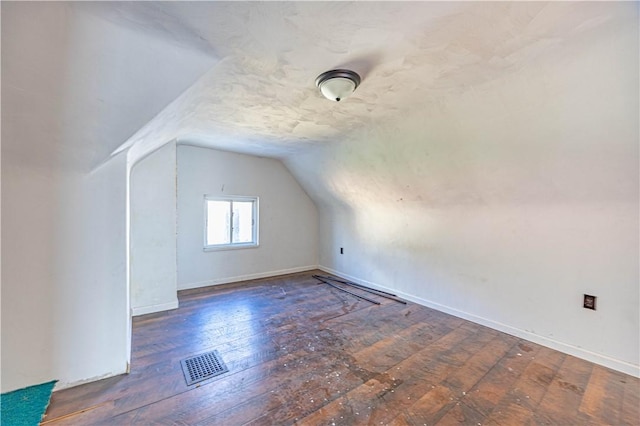 additional living space with dark hardwood / wood-style flooring and vaulted ceiling