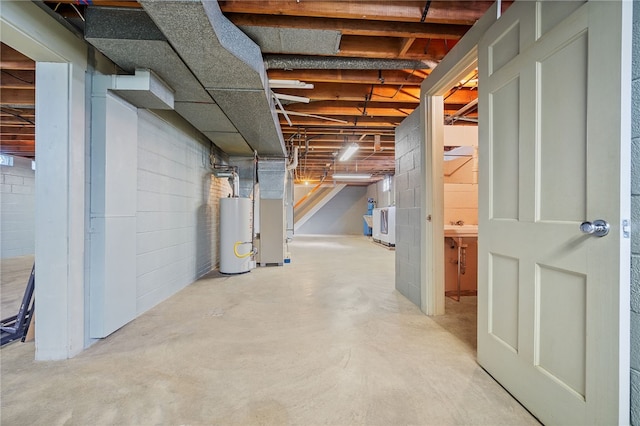 basement featuring heating unit, water heater, and washer / dryer