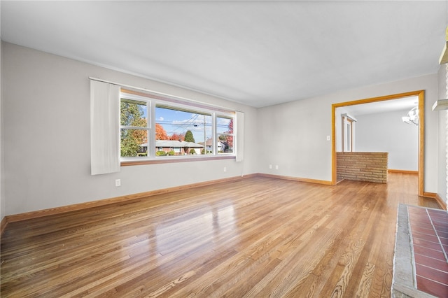 unfurnished living room with light wood-type flooring and a chandelier