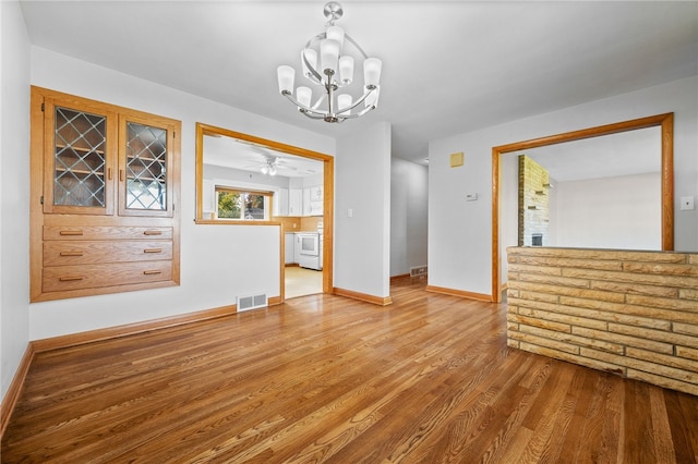 unfurnished dining area featuring ceiling fan with notable chandelier and hardwood / wood-style flooring