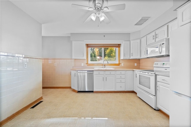 kitchen with white cabinetry, sink, ceiling fan, white appliances, and tile walls