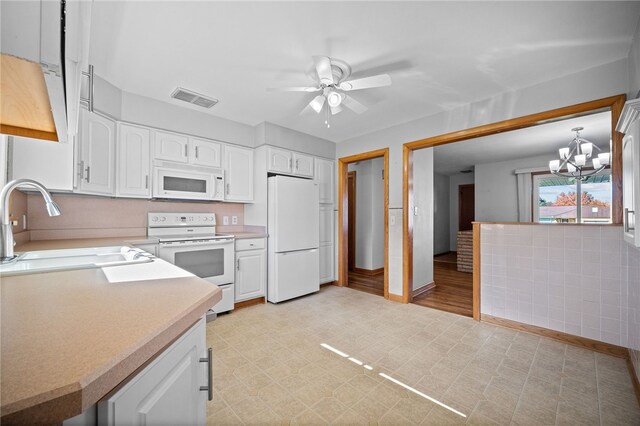 kitchen featuring pendant lighting, white appliances, white cabinets, ceiling fan with notable chandelier, and sink