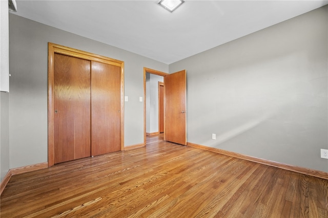 unfurnished bedroom with light wood-type flooring and a closet