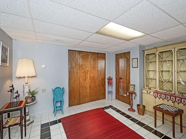 interior space with a paneled ceiling and light tile patterned floors