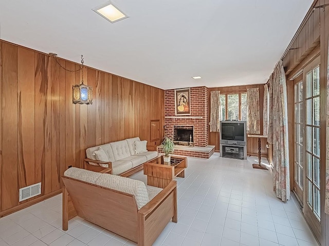 living room featuring a brick fireplace and wooden walls