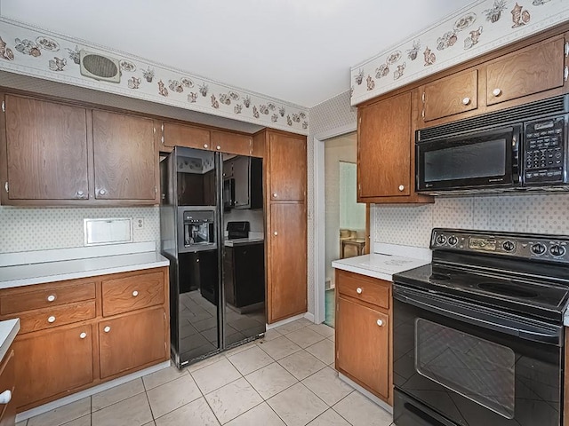 kitchen featuring light tile patterned floors, backsplash, and black appliances