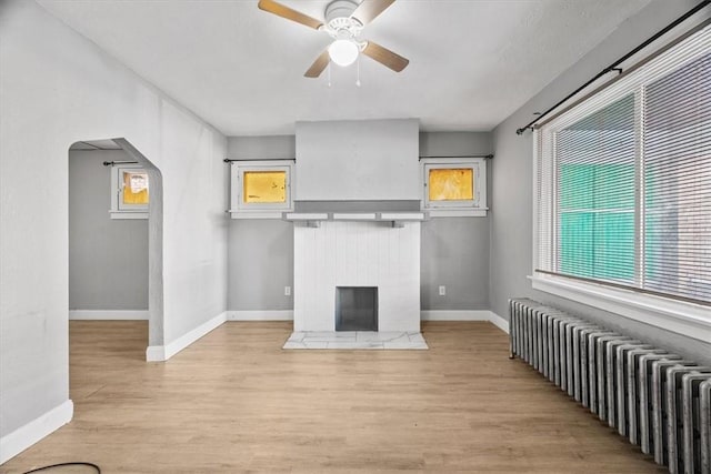 living room featuring radiator, ceiling fan, light hardwood / wood-style flooring, and a healthy amount of sunlight