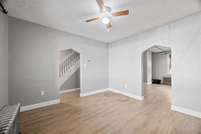 unfurnished living room with hardwood / wood-style floors, ceiling fan, and radiator