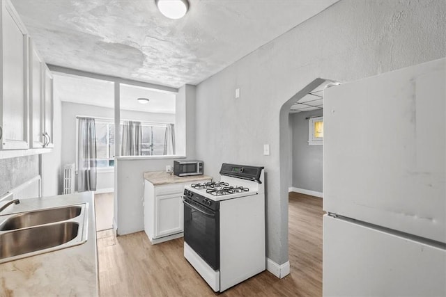 kitchen featuring white cabinets, white appliances, sink, and light hardwood / wood-style flooring