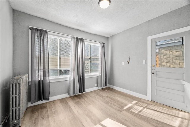 interior space with radiator, a textured ceiling, and hardwood / wood-style flooring