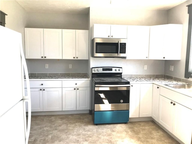 115 Ross St, Confluence Boro, PA 15424 - kitchen featuring stainless steel appliances, light countertops, white cabinetry, and a sink