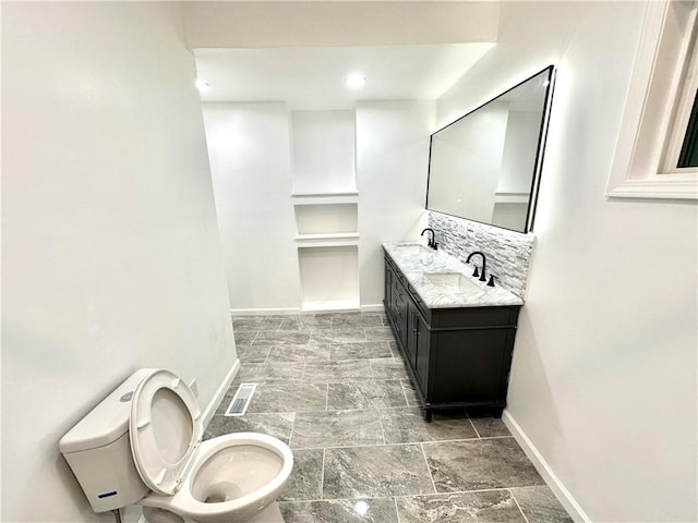 bathroom with vanity, toilet, and backsplash