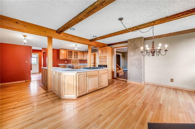 kitchen featuring hanging light fixtures, light wood-type flooring, a textured ceiling, beamed ceiling, and a chandelier