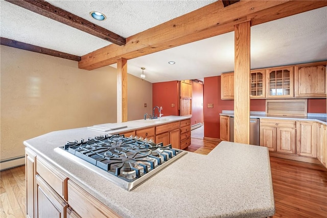 kitchen featuring a center island, light hardwood / wood-style flooring, light brown cabinetry, beam ceiling, and stainless steel gas cooktop