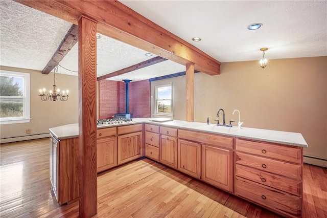 kitchen with decorative light fixtures, kitchen peninsula, sink, and a wealth of natural light