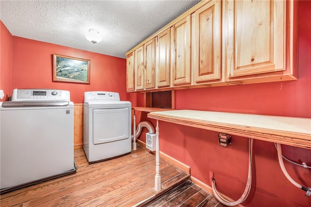 washroom with washer and dryer, cabinets, light wood-type flooring, and a textured ceiling