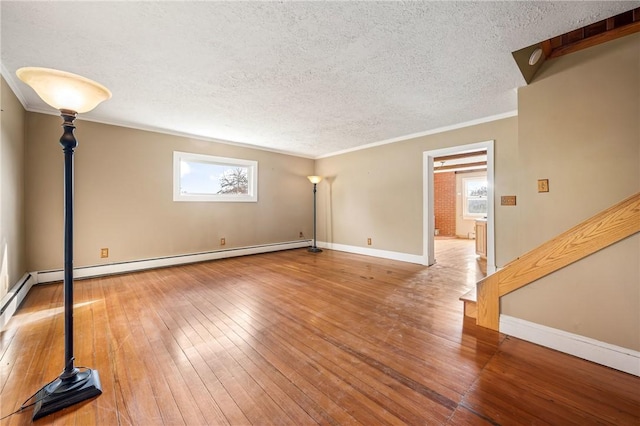 unfurnished room featuring hardwood / wood-style floors, a textured ceiling, a baseboard radiator, and crown molding