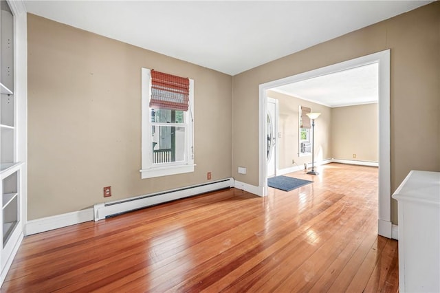 empty room with crown molding, wood-type flooring, and a baseboard heating unit