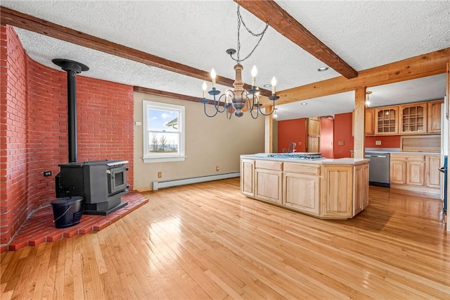 kitchen with dishwasher, a wood stove, a baseboard heating unit, a center island with sink, and beamed ceiling