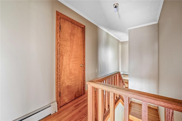 hall with baseboard heating, crown molding, and light wood-type flooring