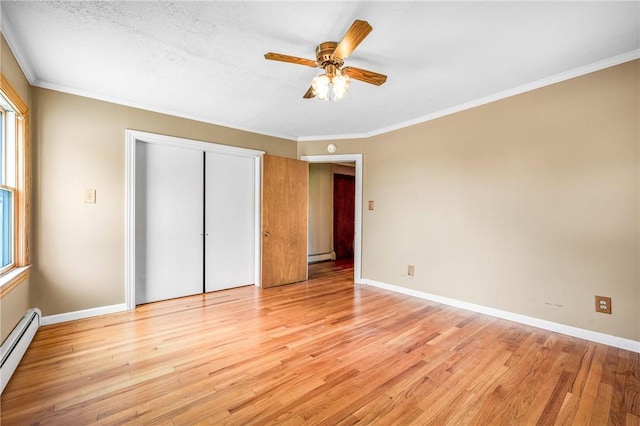 unfurnished bedroom featuring ornamental molding, baseboard heating, ceiling fan, light hardwood / wood-style floors, and a closet