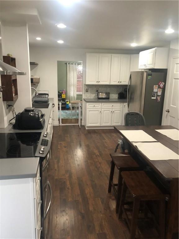 kitchen with stainless steel fridge, dark hardwood / wood-style flooring, backsplash, white electric range oven, and white cabinets