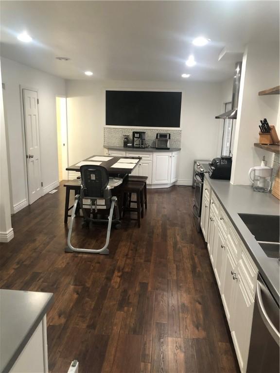 kitchen featuring sink, stainless steel appliances, tasteful backsplash, dark hardwood / wood-style flooring, and white cabinets