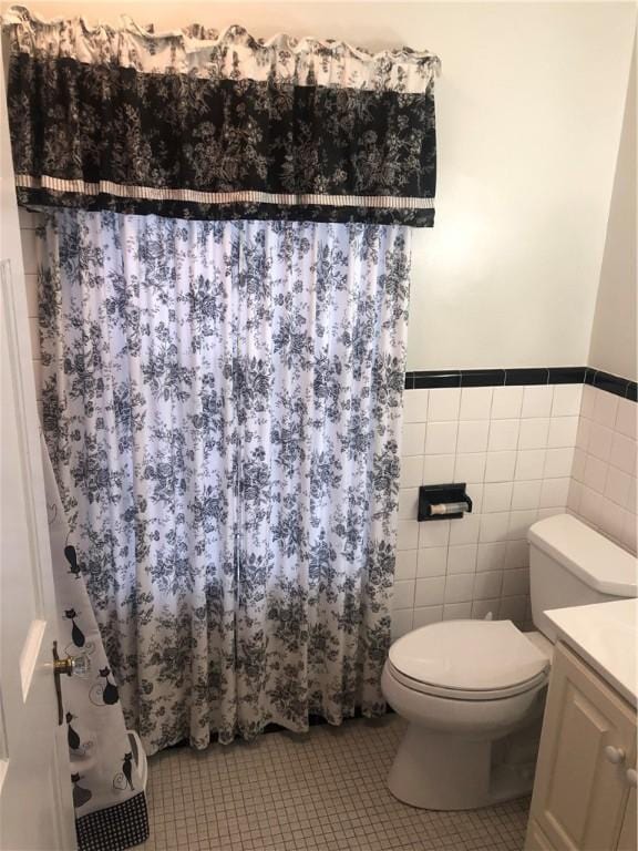 bathroom with tile patterned flooring, vanity, toilet, and tile walls