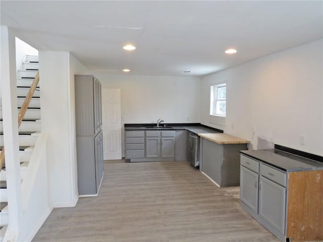 bar with light wood-style floors, recessed lighting, a sink, and stairs