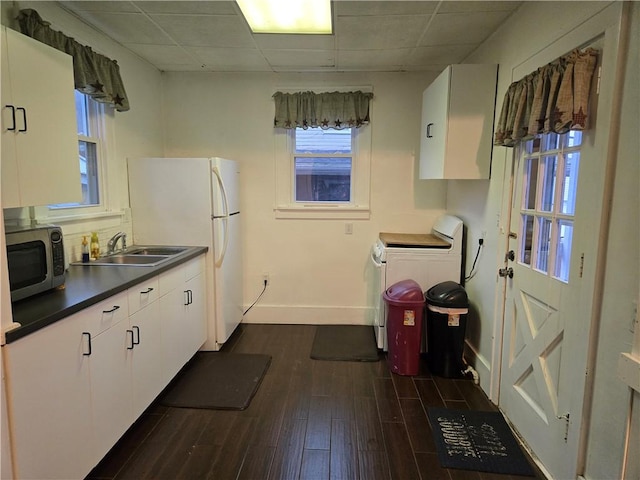 kitchen with white cabinets, dark hardwood / wood-style flooring, washer / clothes dryer, and sink