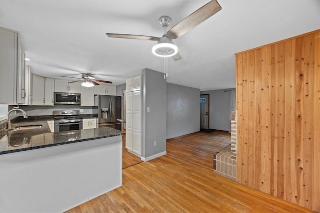 kitchen with white cabinetry, sink, light hardwood / wood-style flooring, kitchen peninsula, and appliances with stainless steel finishes