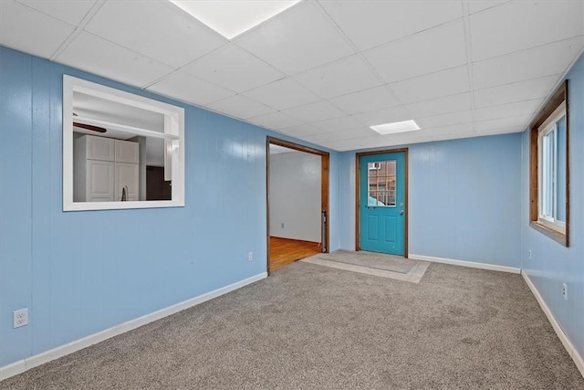 empty room with a drop ceiling, light colored carpet, and plenty of natural light