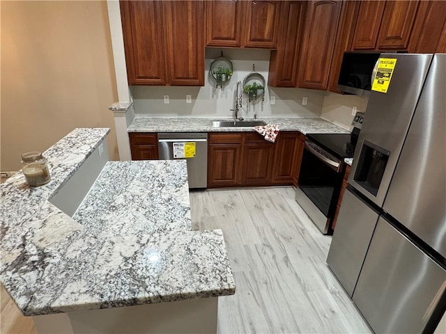 kitchen featuring light stone counters, light wood-type flooring, sink, and appliances with stainless steel finishes