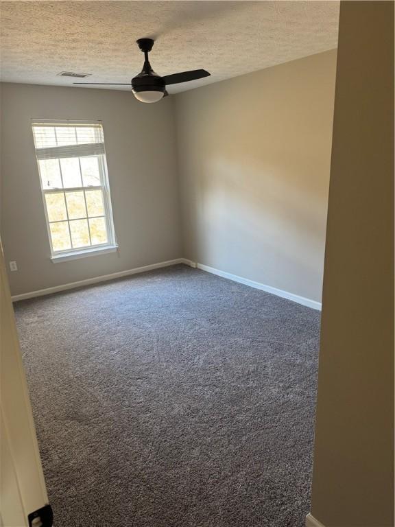 carpeted spare room with ceiling fan and a textured ceiling