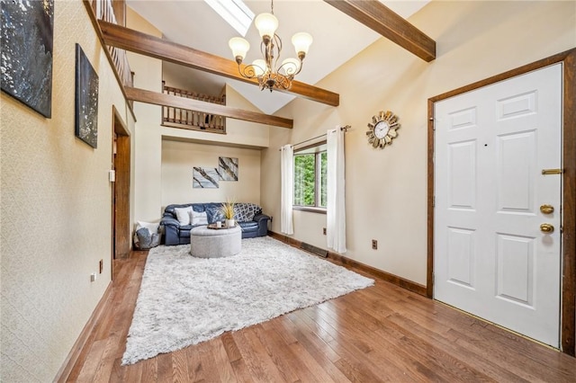 entrance foyer featuring hardwood / wood-style floors, lofted ceiling with beams, and an inviting chandelier