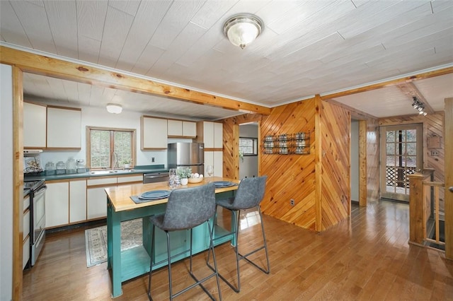 dining space with wood walls, sink, and light wood-type flooring