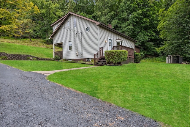 view of side of home with a lawn, a shed, and a deck